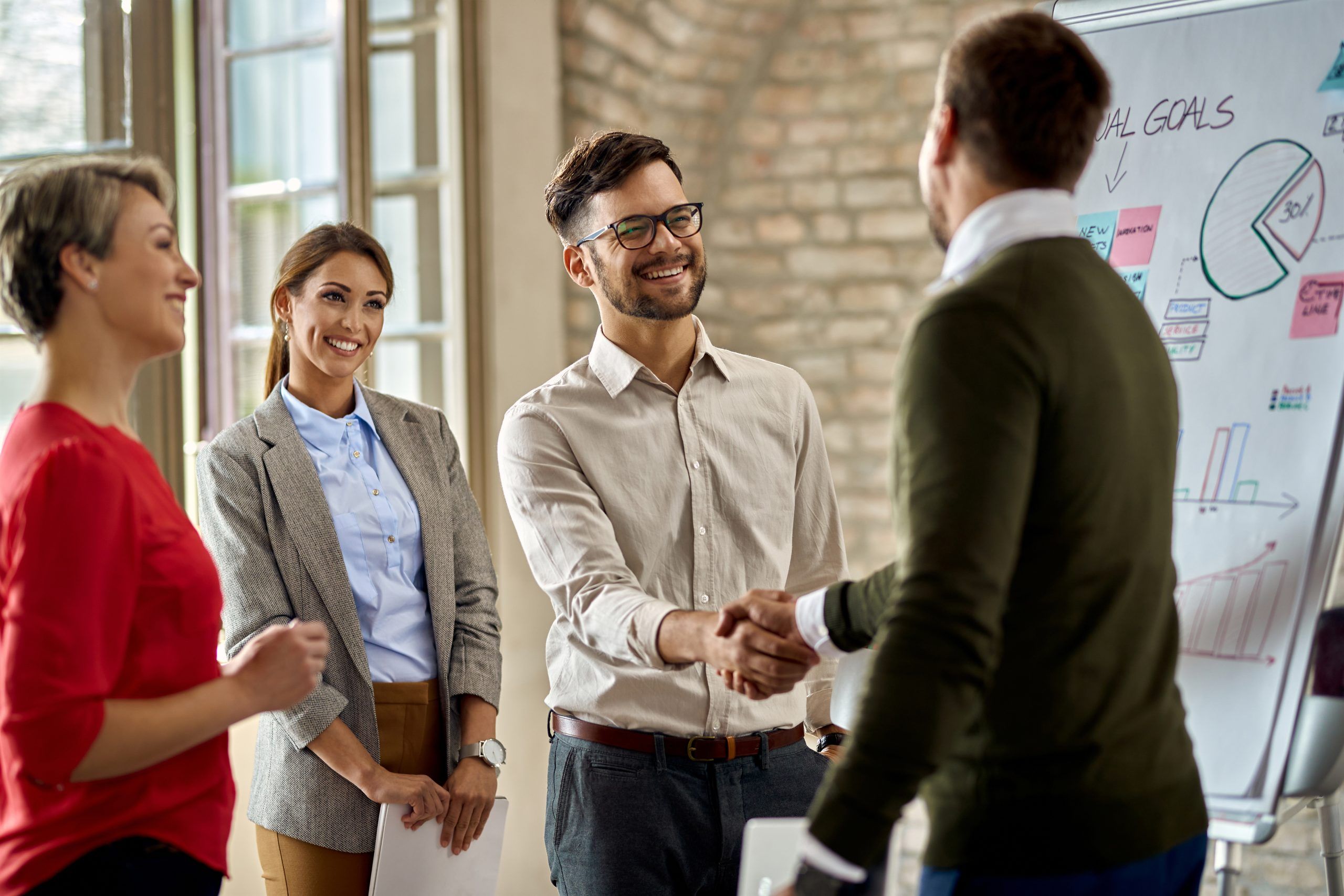 happy coworkes shaking hands after business presentation office 1 scaled 801f31a9