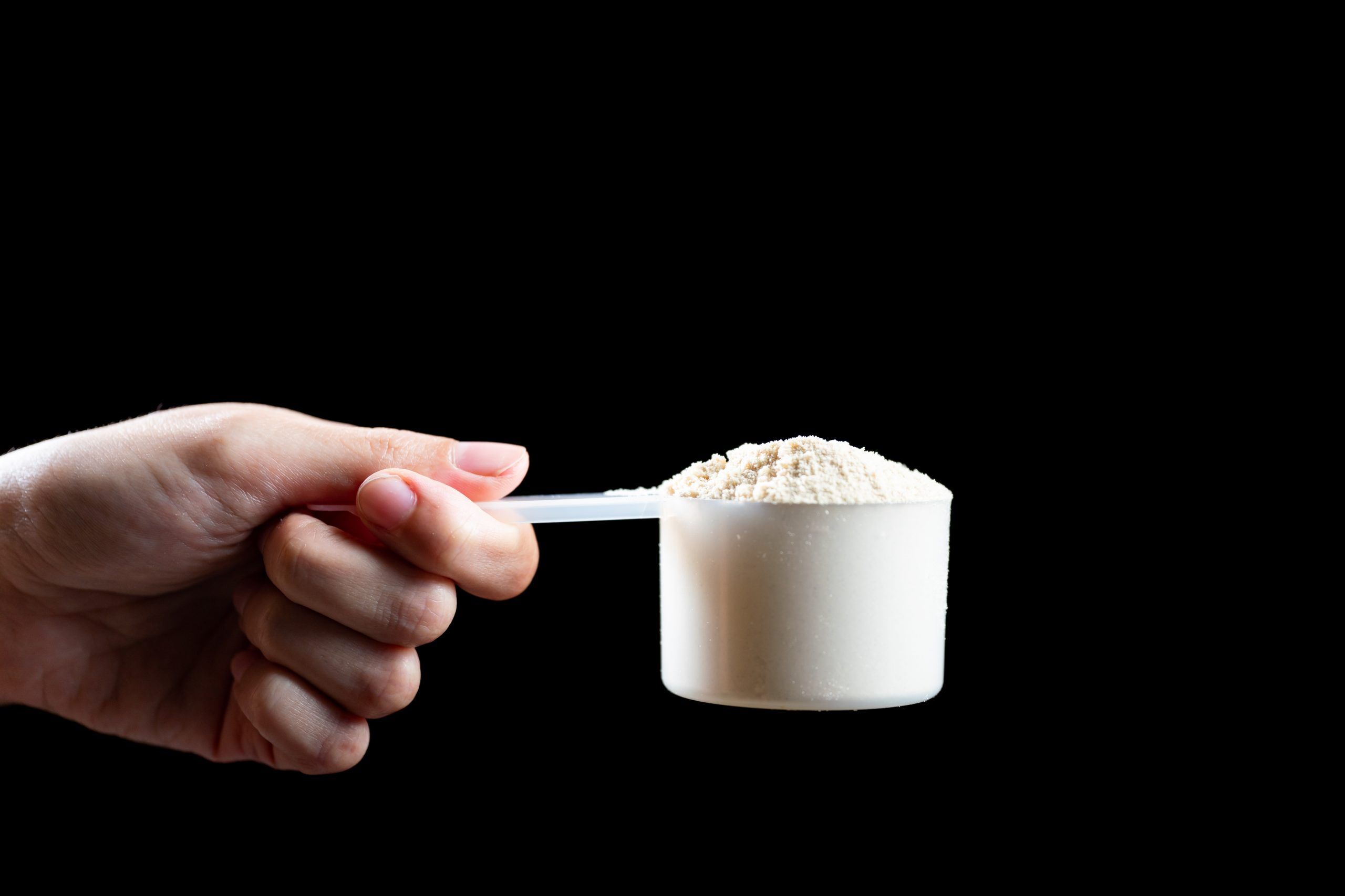 close up women hand holding measuring scoop whey protein preparing protein shake scaled c32cbfe0